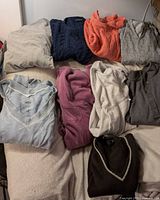 Group shot of nine sweaters arranged on bed