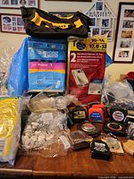 Overall lot showing DeWalt bag, vacuum bag packages, tape measures, faucet, vent filters, knobs