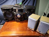 Front view of Sony stereo main unit with attached Sony speakers and Aiwa speaker pair on wooden surface