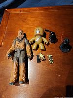 Group shot of all Star Wars figures and accessory on wooden surface