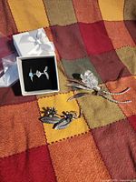 All five items laid out on fabric: three rings in box, sterling brooch, crystal flower