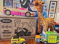 Group shot showing sealed Tonka dump truck box, Geoffrey plush, LOL car, die-cast panel truck, plastic utility truck