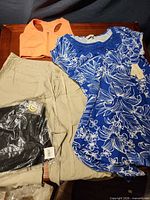 Overview of all four clothing items laid out: beige capris, blue floral dress, orange sports bra, sealed black leggings
