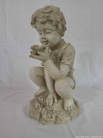 Full side view of resin boy statue with bird
