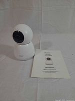 Front view of white itek pan/tilt camera and instruction manual