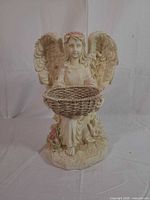 Front view of resin angel holding woven-look planter basket