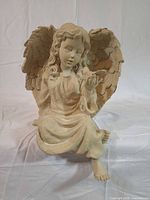 Full view of seated resin angel statue