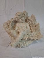 Front angled view of cherub figurine in leaf cradle
