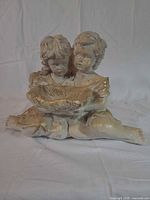 Full view of plaster figurine showing two children holding bowl