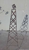 full view of rust-brown metal lattice obelisk trellis casting shadow
