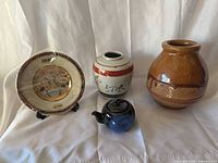 group shot showing all five items – plate (in wrap) on stand, ginger jar, teapot, brown vase