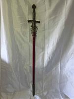 Full view of sword in red velvet scabbard showing brass-tone hilt and fittings