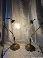 Both lamps illuminated showing different frosted shades and ornate bases
