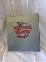 front of grey Wheels and Wings binder