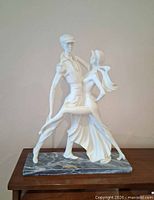 Full view of white dancing couple sculpture on grey marble base