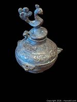 Overall view of bronze inkwell showing peacock finial and decorative body