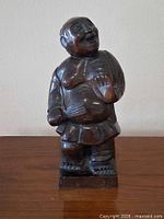 Front view of dark wooden laughing Buddha statue on base