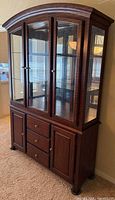 Front view of full cabinet showing glass doors, arch top, lower storage