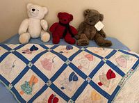Quilt draped in front of three teddy bears