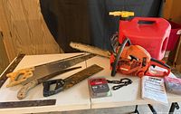Overall view showing chainsaw, fuel can, hand saws, measuring tools, spare chains, manual