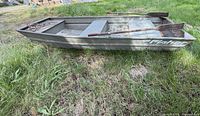 Port side view of Fisher 1032 jon boat on grass with paddles inside