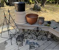 assortment of planters, stands and wrought iron pieces displayed on bench and deck