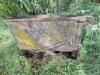 Side view of rusted ore bucket partially buried