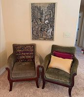 Two chairs with pillows and framed art displayed together
