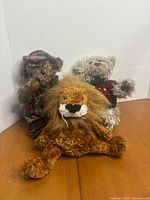Front view of three Ganz plush toys: lion, plaid bear, sweater bear