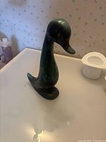 Full view of green ceramic duck figurine front profile
