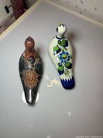 Top view of both ceramic bird figurines showing color schemes and hand-painted details
