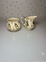Cream porcelain sugar bowl and creamer displaying floral gold decoration