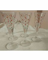 Six clear glass cordial glasses with orange polka dots standing upright