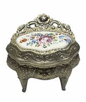 Front view of ornate silver-tone trinket box showing porcelain floral lid and four legs