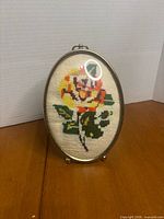 Front view of oval framed needlepoint showing entire rose design and frame