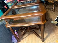 Two wood and glass curio tables side by side showing tops and legs
