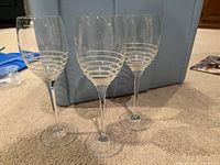 Three clear wine glasses with striped design on carpet