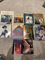 Front view of nine art books laid out on carpet