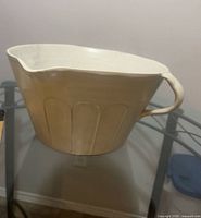 Beige ceramic planter with handle on glass table
