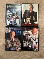 Front view of four DVD cases: NHL Classics Greatest Moments, Don Cherry documentary, Rock’em Sock’em Hockey 23, Rock’em Sock’em Hockey 24