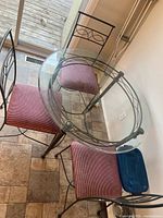 Round glass-top table with four matching chairs showing design and upholstery