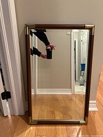 Front view of rectangular mirror showing wood frame and brass corners