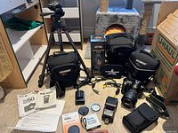 Full layout showing Nikon D50 camera with lens, Sunpak flash, battery, charger, two tripods, three camera bags, filter, manuals and accessories