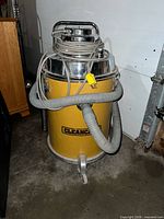 Front view of yellow Cleancare wet/dry vacuum with hose and cord