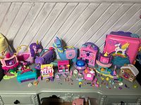 Overview of multiple Polly Pocket compacts, animal purses, micro dolls and accessories on table