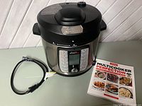 Front view of Power Quick Pot with power cord and cookbook