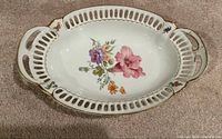 Top view of oval porcelain platter showing floral motif and reticulated gold-trimmed rim