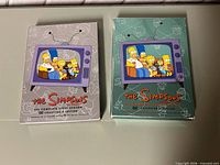 Front view of both Season 1 grey and Season 2 teal DVD box sets