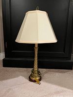 Front view of gold-tone textured metal column lamp with ivory shade and power cord