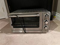 Front view of stainless steel toaster oven showing control dials and glass door